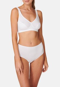 Weißer, dehnbarer Baumwoll-Bralette mit breiten Trägern und unterstützendem Design. Getragen mit passenden hochgeschnittenen weißen Baumwoll-Slips. Glatte Textur.