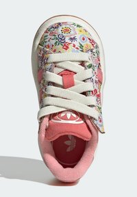 Teniska s květinovým vzorem s bílým plátěným svrškem, růžovými akcenty a bílými tkaničkami. Obsahuje polstrovanou růžovou stélku s logem.