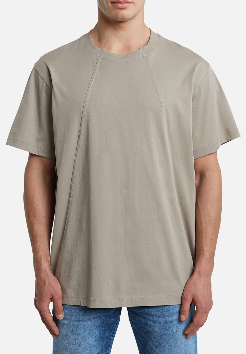 T-shirt gris clair en coton. Présente une coupe décontractée, des manches courtes et un col rond côtelé. Texture lisse avec des coutures minimales.