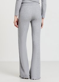 Pantalon gris évasé à côtes avec une texture douce, doté d'une taille haute et d'ourlets festonnés pour plus de détails.
