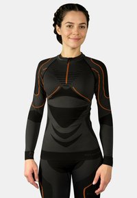 Long-sleeve activewear top in black with grey accents. Features a zip neck, textured panels, and orange detailing, designed for fit and flexibility.