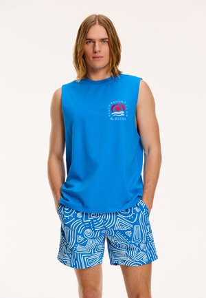 Blauw mouwloos shirt met een ronde grafisch ontwerp en tekst, gecombineerd met blauwe shorts versierd met witte abstracte patronen en lijnen.