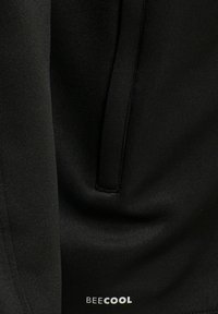 Tejido atlético negro con una textura suave, presenta un bolsillo oculto con cierre de cremallera. Logotipo "BEECOOL" impreso en blanco.