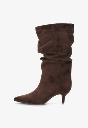 Botín de ante marrón con diseño holgado, punta puntiaguda y tacón bajo tipo kitten. El material tiene un acabado suave y texturizado.
