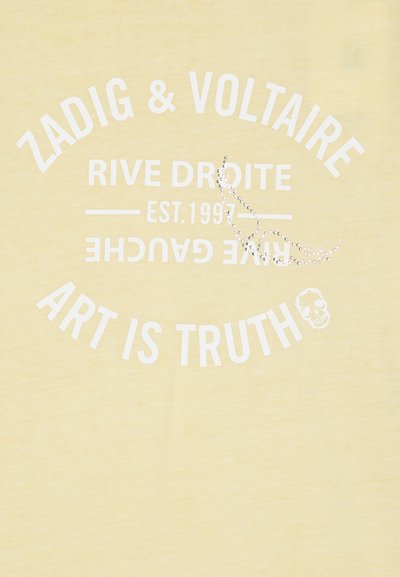 Camiseta de algodón amarilla con texto impreso en blanco: "ZADIG & VOLTAIRE", "RIVE DROITE" y "EL ARTE ES VERDAD", con un gráfico de calavera y piedras decorativas.