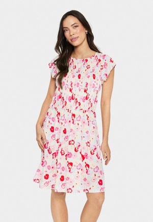 Blumenkleid mit einem pastellrosa Hintergrund und roten sowie rosa Blumen, kurzen, fließenden Ärmeln und einem gerafften Bund, das oberhalb des Knies endet.