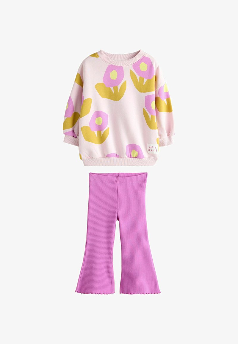 Top de manga larga rosa con estampado floral en amarillo y rosa y etiqueta "Happy Days", combinado con pantalones acampanados rosa sólidos de canalé.