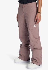 Helle mauve Schneeanzugshose in lässigem Schnitt, mit Gürtelschlaufen, zwei Knöpfen, Cargo-Taschen und einem DC-Logo-Patch an der Seite.