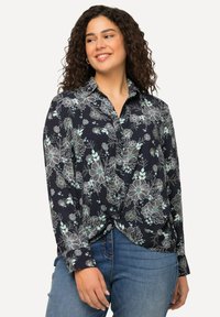 Camicia azzurra navy con motivi floreali in blu chiaro e bianco, con colletto, maniche lunghe e dettaglio anteriore annodato.