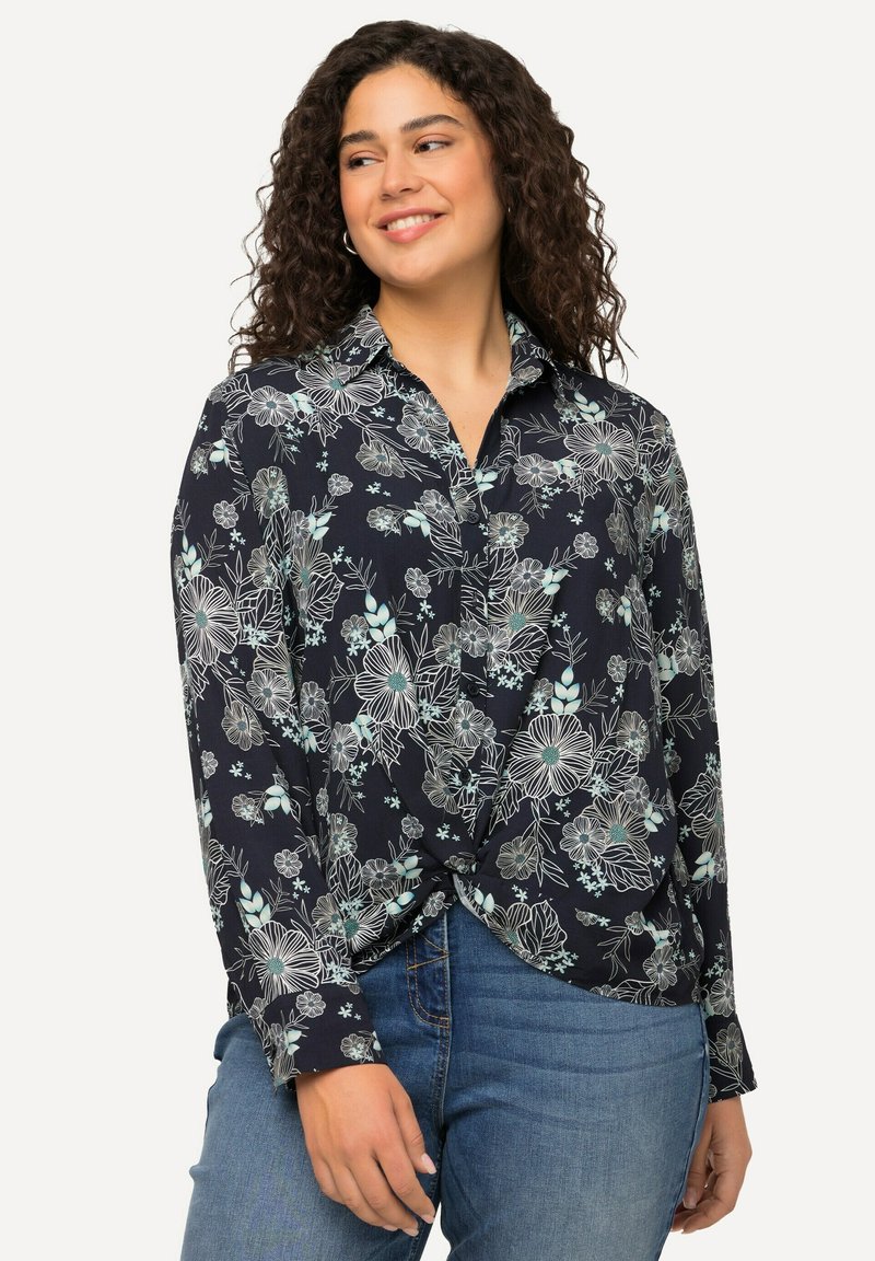 Camicia azzurra navy con motivi floreali in blu chiaro e bianco, con colletto, maniche lunghe e dettaglio anteriore annodato.