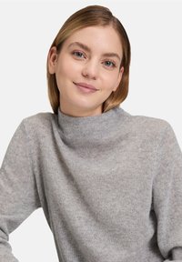 Light grey, high-neck sweater made of soft knit material. Features long sleeves and a relaxed fit, with a smooth texture throughout.