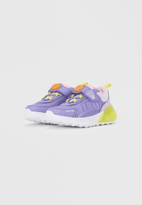 Zapatillas deportivas moradas con suela blanca, con detalles en amarillo neón, lengüeta rosa y un botón naranja. "LOLA BUNNY" impreso en el lateral.