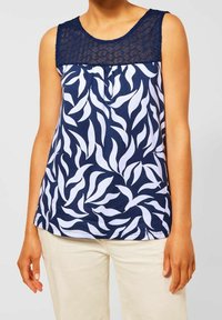 Mörkblå ärmlös topp med ett blommigt vitt mönster, med en texturerad spetsliv och en avslappnad passform, tillverkad av mjukt, andningsbart tyg.