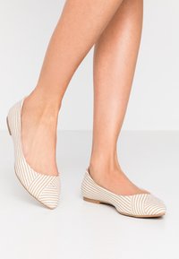 Randiga ballerinas i beige och vit tyg, med rund tå, låg klack och skurna sidor. Texturerad ovandel med diagonala ränder.