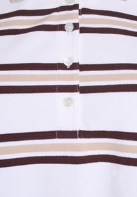 Chemise polo blanche avec des rayures horizontales marron et beige, dotée d'une patte de boutonnage ornée de boutons nacrés. Texture douce.