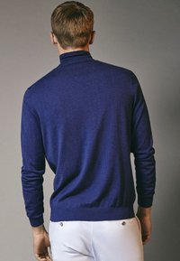 Maglione girocollo blu navy con collo alto, polsini e orlo a coste. Realizzato in morbido tessuto a maglia, presenta una finitura liscia e testurizzata.