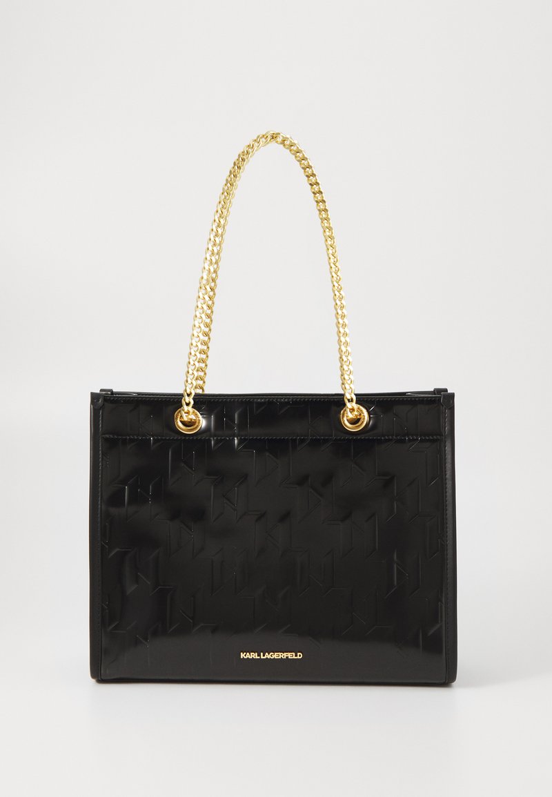Borsa a tracolla in vernice nera con un motivo geometrico testurizzato, manici in catena dorata e un accento dorato del logo nella parte inferiore.