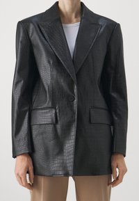 Blazer en cuir embossé façon crocodile noir avec col cranté, un bouton unique et deux poches avant ; texture lisse et coupe cintrée.