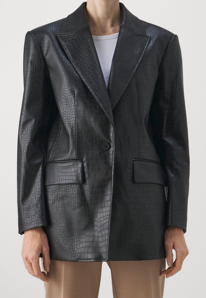 Blazer en cuir embossé façon crocodile noir avec col cranté, un bouton unique et deux poches avant ; texture lisse et coupe cintrée.