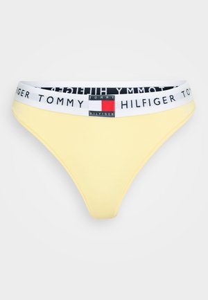 Bañador de algodón amarillo estilo bikini con una cinturilla elástica blanca que presenta la marca y el parche del logo "TOMMY HILFIGER" en negro y rojo.