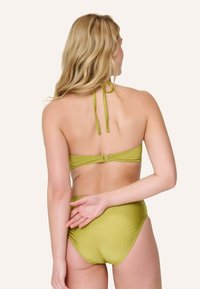 Set bikini verde con design a collo alto, laccetti regolabili e slip a vita alta. Texture liscia con dettagli minimi.