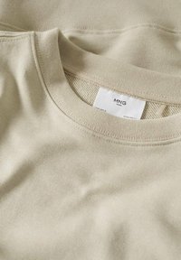 Maglione in cotone beige con scollo rotondo, presenta un colletto a coste e un'etichetta bianca con il nome del marchio "MNG MAN" all'interno del colletto.
