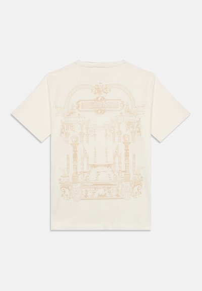 Μπλούζα από βαμβάκι σε κρεμ χρώμα με λεπτομερή, ανοιχτό πορτοκαλί γραφικό με αρχιτεκτονικά στοιχεία και το κείμενο "VERSACE" στην πλάτη.