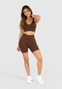 Bruine sportbeha en bijpassende fietsshorts van rekbaar materiaal, met een aansluitend ontwerp, een ronde halslijn en een hoge taille.