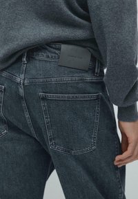 Ciemne dżinsy z denimu z wyblakłym wykończeniem, z tylnymi kieszeniami i czarną skórzaną metką "Massimo Dutti" na pasku talii.