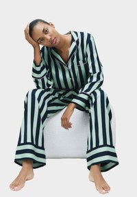 Set di pigiama a righe in blu scuro e verde menta, composto da una camicia con bottoni dotata di taschino e pantaloni larghi con bordi.