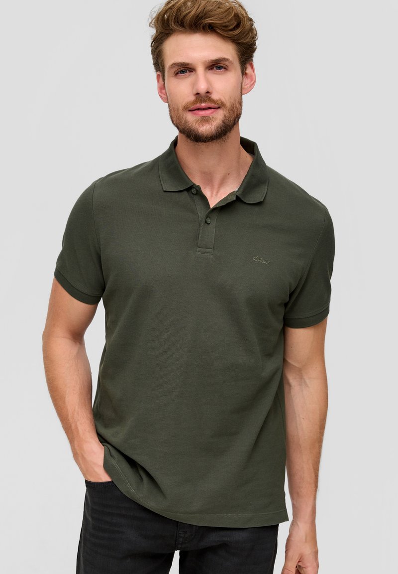 Polo shirt vert foncé en tissu texturé, avec un col classique, une patte de boutonnage et des manches courtes. Détail de logo simple sur la poitrine.