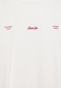 Biała koszulka z czerwonym tekstem: "Sweet Ice" na środku, "Cold enough to last" po lewej i "Hot enough to break" po prawej.