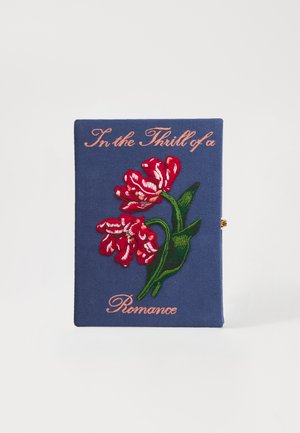 Clutch têxtil com um fundo azul escuro, flores vermelhas bordadas e a frase "Na Emoção de um Romance" em rosa.