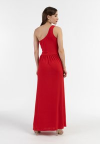 Abito lungo rosso con spalla sola, fitted in vita, tessuto fluido, orlo fino a terra e leggero lucido.