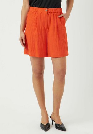 Shorts plissés orange avec une taille élastique, dotés de poches latérales et d'une fermeture à bouton, fabriqués à partir d'un tissu texturé léger.