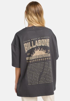 Übergröße schwarzes T-Shirt aus Baumwolle mit einem Grafikdruck auf der Rückseite, der Text und Sonnenmotive in Beige- und Goldakzenten zeigt.