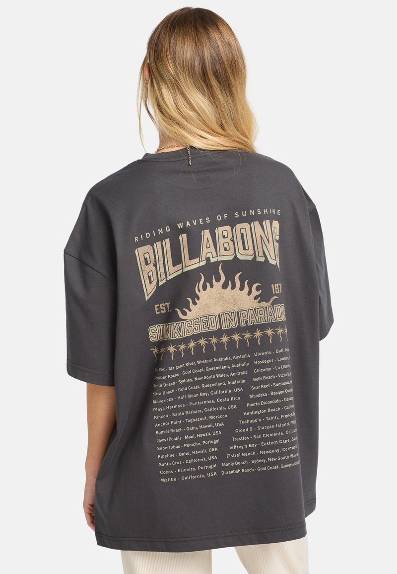 Overdimensioneret sort t-shirt lavet af bomuld, med et grafisk tryk på ryggen, som har tekst og solmotiver i beige og guld accenter.