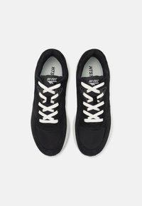 Schwarze Sportschuhe aus Mesh- und Wildledermaterialien, mit weißen Schnürsenkeln und einer markanten Gummisohle; mit einem Logo auf der Zunge.