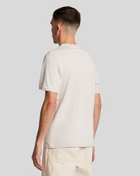 Light beige cotton t-shirt with a crew neckline, short sleeves, and straight cut, displayed from the back. Smooth texture and casual design.