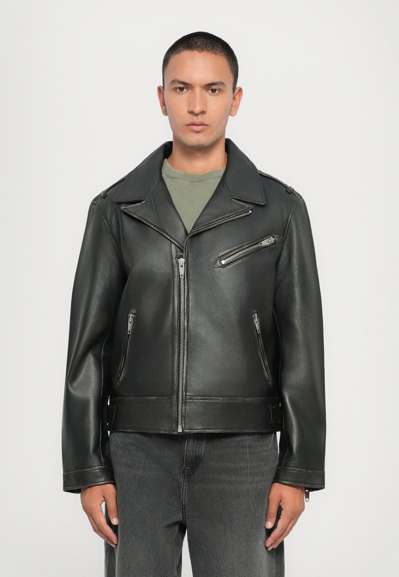 Μαύρο δερμάτινο μπουφάν μοτοσικλέτας με φαρδύ γιακά, φερμουάρ μπροστά και δύο πλαϊνές τσέπες. Υφή επιφάνειας με ορατές ραφές.