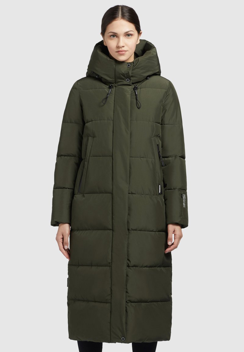 Cappotto lungo e verde oliva in stile puffa, con un alto colletto, grande cappuccio, lacci elastici, bottoni a scatto e due tasche laterali.