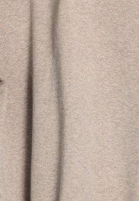 Lichtbeige, zachte katoenen stof met een gladde textuur. Heeft een eenvoudig, ongecompliceerd ontwerp. Geen prominente patronen of hardware zichtbaar.