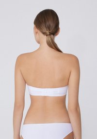 Biały bikini top bez ramiączek o gładkiej fakturze, charakteryzujący się prostym wzornictwem i zapięciem z tyłu, uzupełniony pasującymi białymi majtkami bikini.