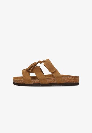 Sandalo ciabatta in suede marrone con suola in sughero, due ampie fasce, nodo regolabile e dettaglio di nappine sulla parte superiore, suola esterna nera e strutturata.