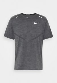 Harmaa urheilupaita, joka on valmistettu tekstuurista kankaasta, jossa on lyhyet hihat, pyöreä kaula-aukko, hienovaraiset yksityiskohdat ja valkoinen Nike-logo edessä.