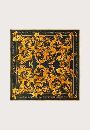Square silk scarf featuring intricate gold baroque-style designs on a black background, with text reading "Versace Jeans Couture" along the edges.