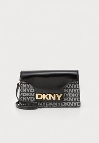 Pochette en tissu laqué noir et à motifs avec le logo doré "DKNY". Dispose d'une fermeture à rabat et d'une bandoulière amovible. Forme rectangulaire.
