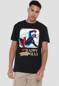 Young man wearing black t-shirt with Spider-Man in Santa hat swinging web and text "Happy THWIP-MAS" with festive bells background.