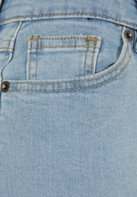 Svetlo modri jeans iz denima z kontrastnimi zlatimi šivi, ki imajo majhen zadnji žep in podrobnost z kovinsko gumbom.
