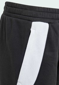 Pantalons de survêtement noirs avec un panneau latéral blanc, fabriqués en coton doux, dotés d'une taille élastique et de poches latérales pour plus de fonctionnalité.